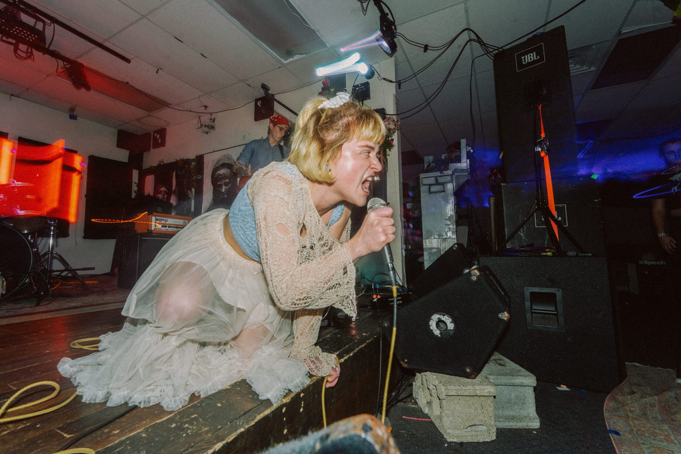 Woman on a stage screaming into a microphone.
